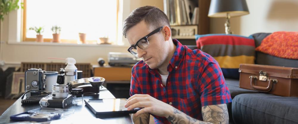 man with glasses using a tablet